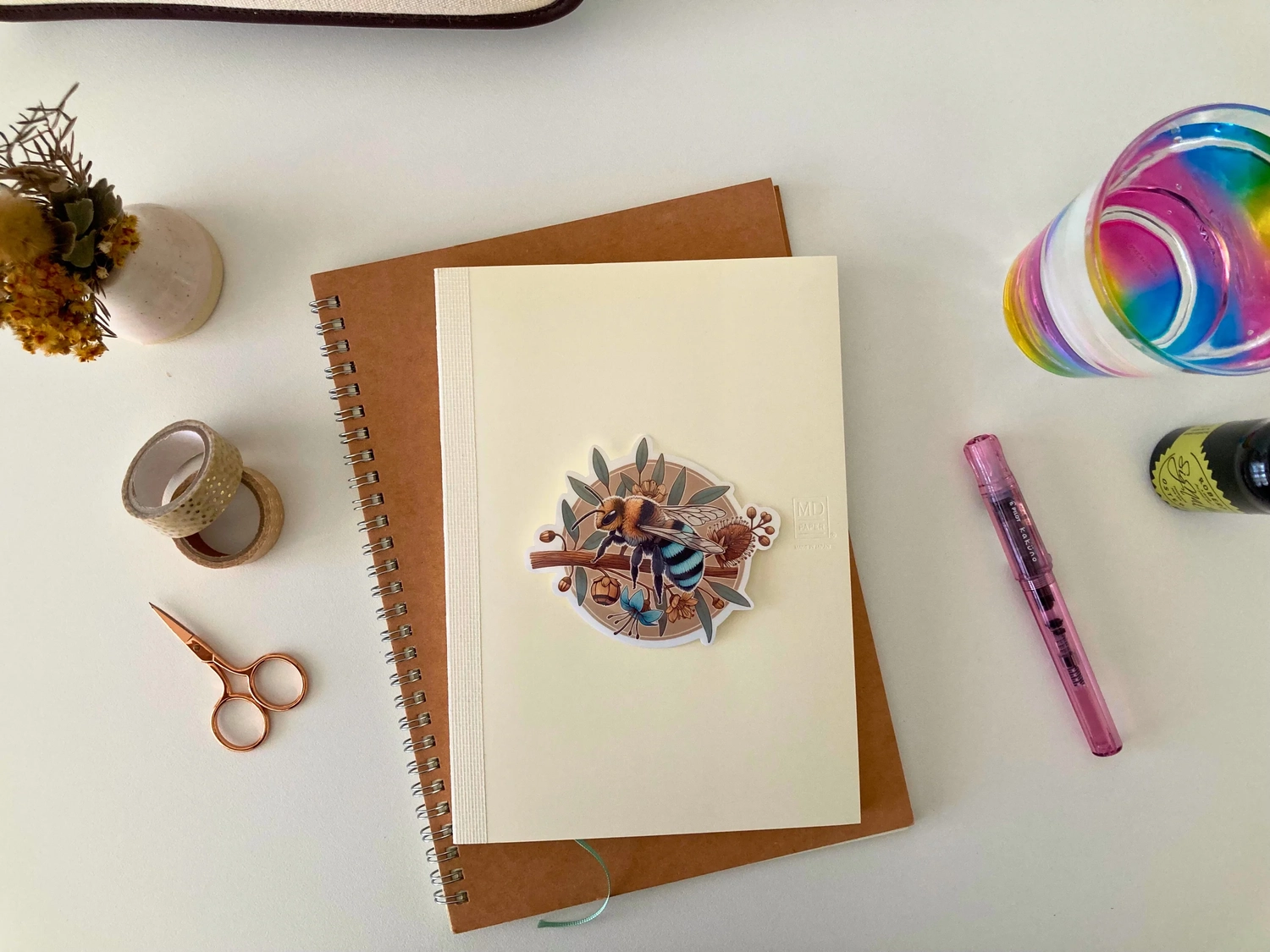 Decorative stickers for journaling and scrapbooking blue banded bee sticker sits on top of a midori traveller's notebook
