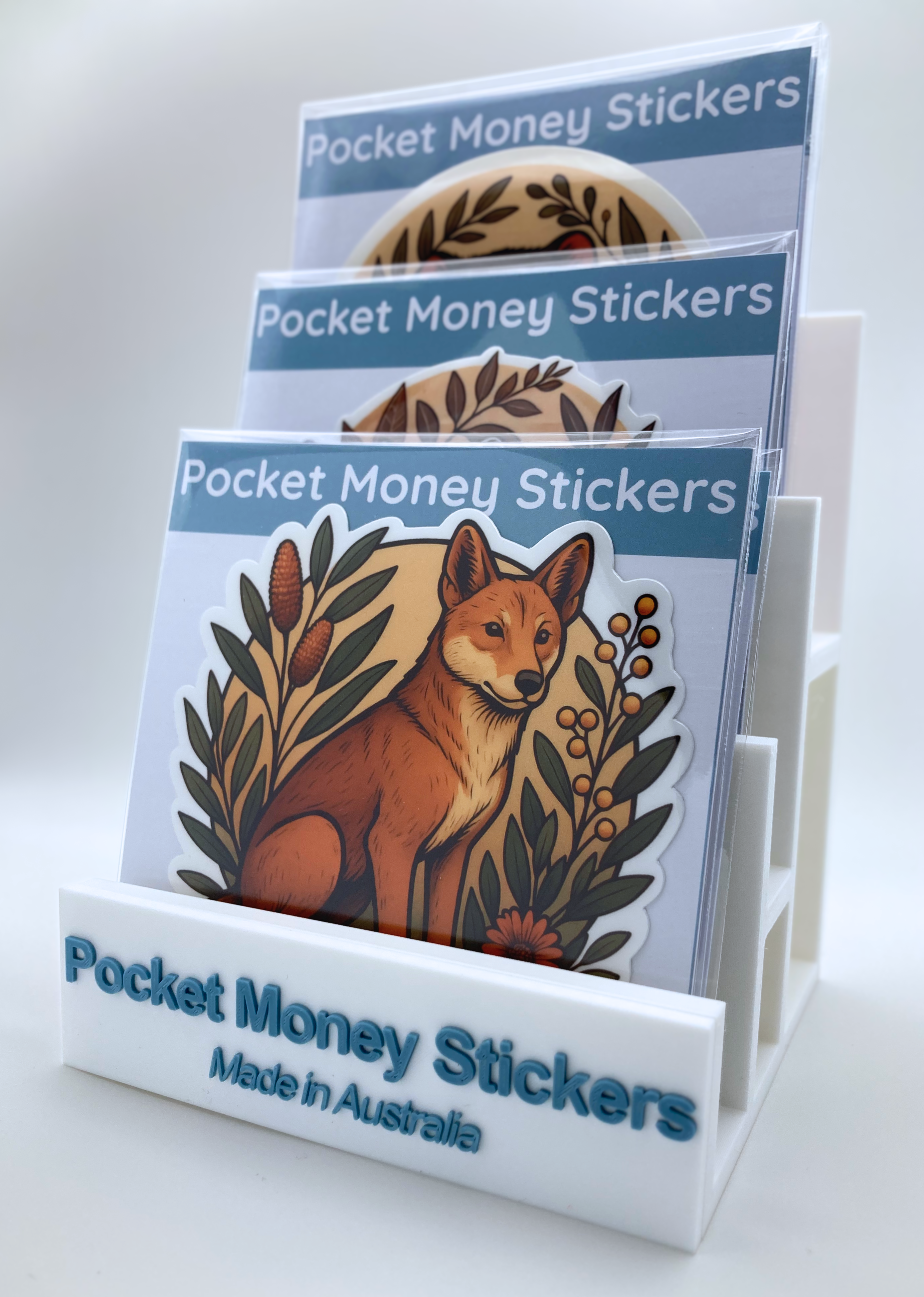 Packaged single stickers on a display stand, a dingo sticker is visible